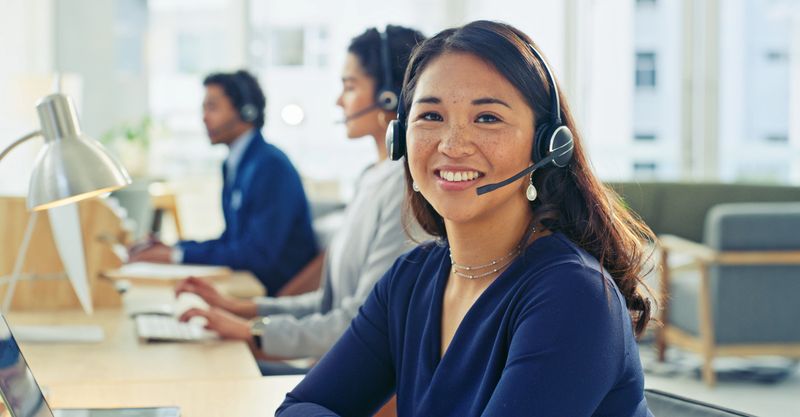 A group of young professionals working in a modern office environment engaging with clients using headsets. The image conveys collaboration, customer service, teamwork, efficiency, and workplace focus, showcasing corporate work culture.