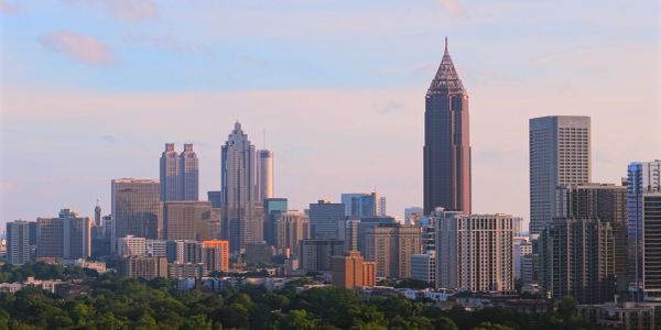 City skyline at sunset with tall buildings and trees.