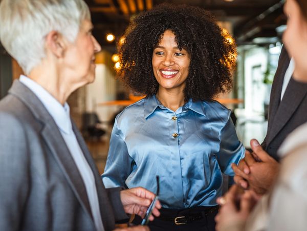Diverse colleagues smiling and chatting in a modern office setting.