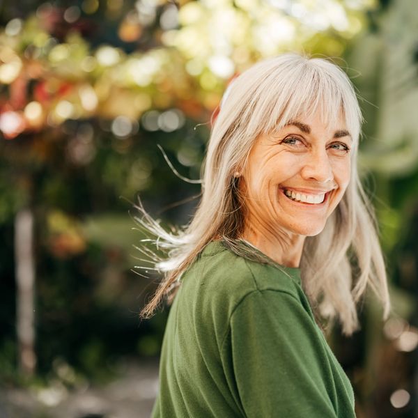 Smiling older woman with gray hair outdoors.
