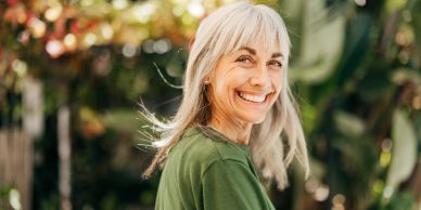 Smiling older woman with gray hair outdoors.
