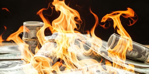 Rolled and flat US dollar bills burning with bright flames.