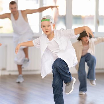 Young boy dancing in a studio with two others.