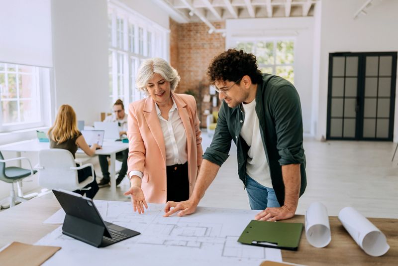 Engineer analyzing blueprints and sustainable design plans at a consulting firm.