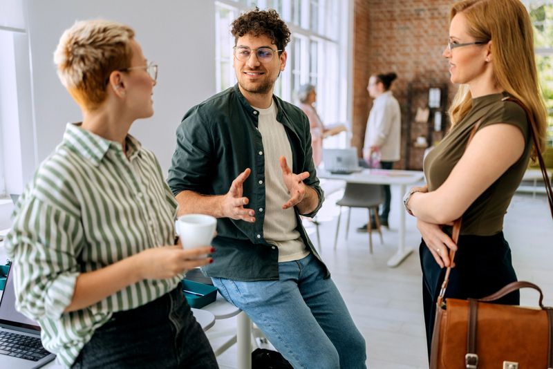 Business team in office having discussion during break. Male and female business professionals having meeting inside office during coffee break.