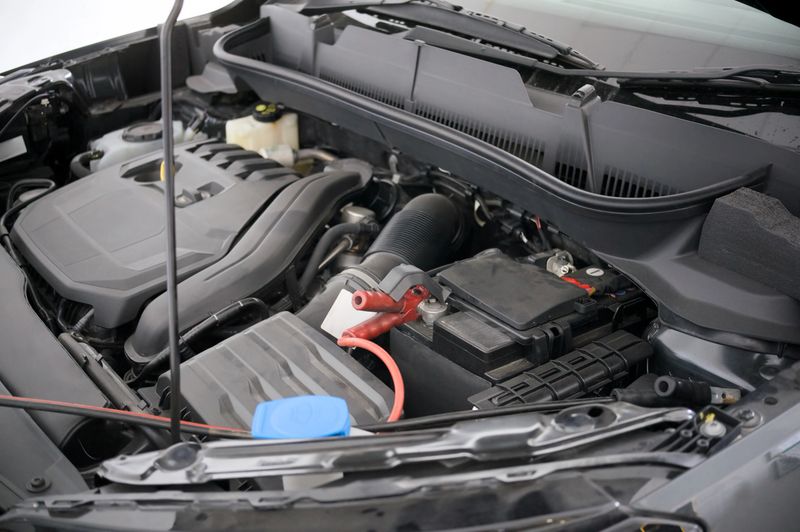 Close-up of a car engine showcasing components during a maintenance check by an automotive technician.