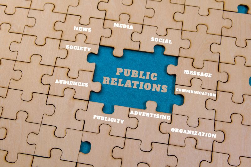 Puzzle pieces depict key public relations concepts: media, society, and communication strategies.