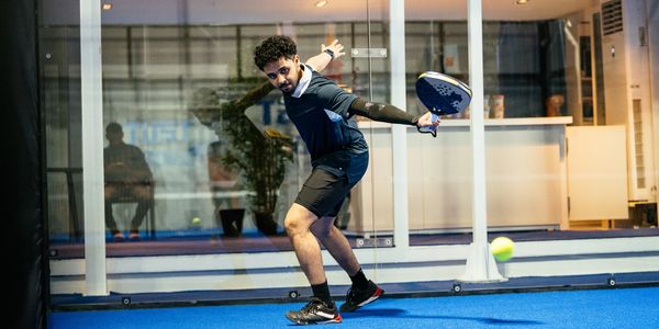 Man playing padel on an indoor court.