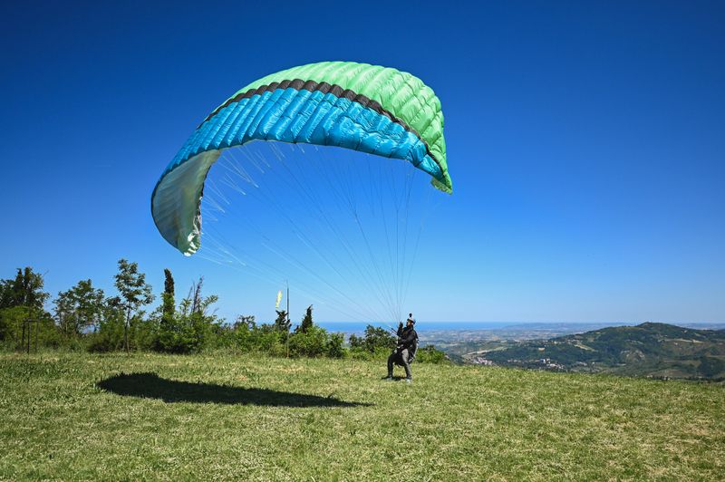 Paraglider taking off from a hilltop on a sunny day