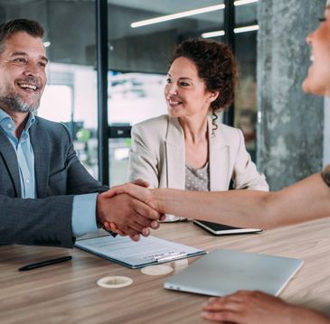 Happy couple holding car keys at a dealership, smiling excitedly.