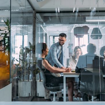 Team collaborating in a modern office meeting room with glass walls.