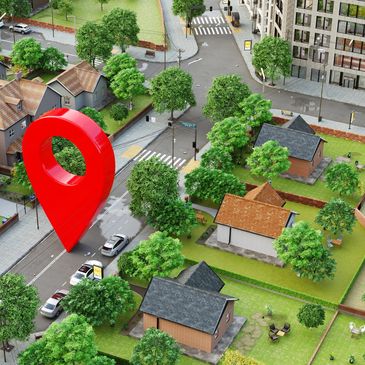 A giant red location pin stands on a city street surrounded by houses and trees.