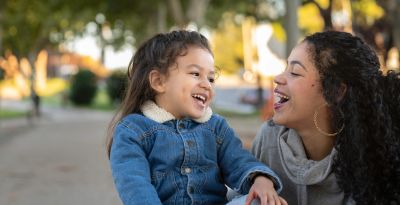 Mother and daughter laughing together outdoors.