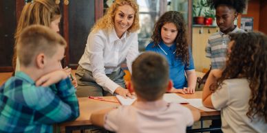 Teacher engaging with young students at a table.