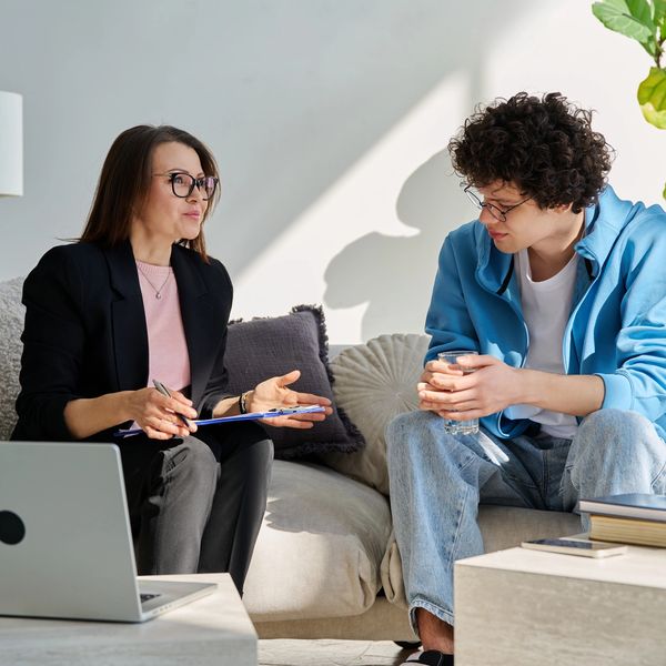 A woman and young man having a serious conversation on a sofa.