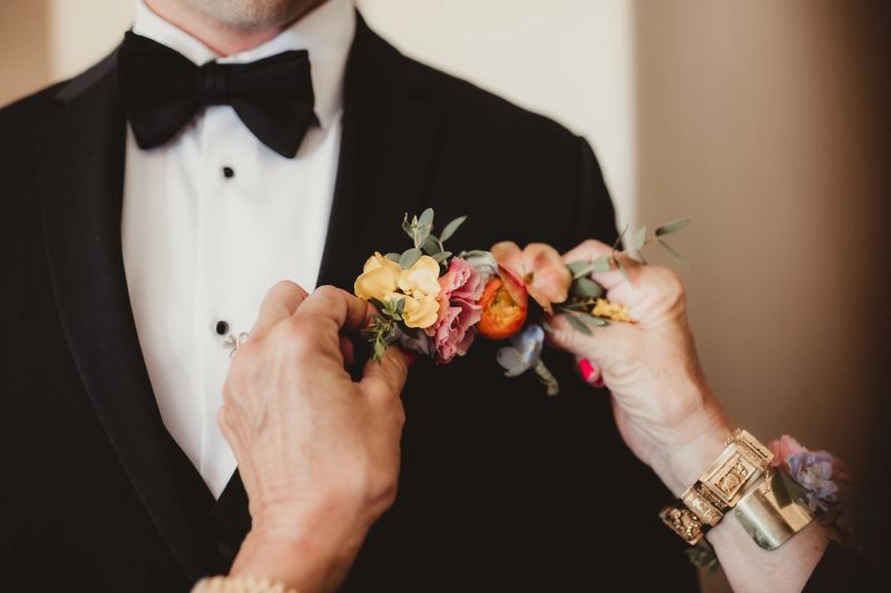 Mother of groom pinning on flower boutonniere for wedding ceremony