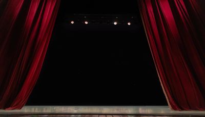 Open red theater curtains revealing an empty stage.