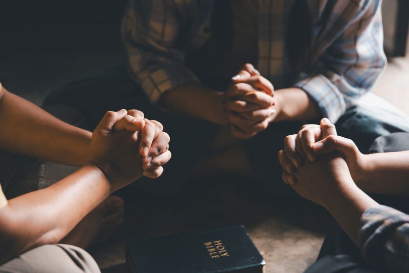 Close up group christians hands pray to God with spiritual faith on holy bible in catholic church. religion worship prayer ask god bless grace jesus believe. Christianity religion prayer holy worship