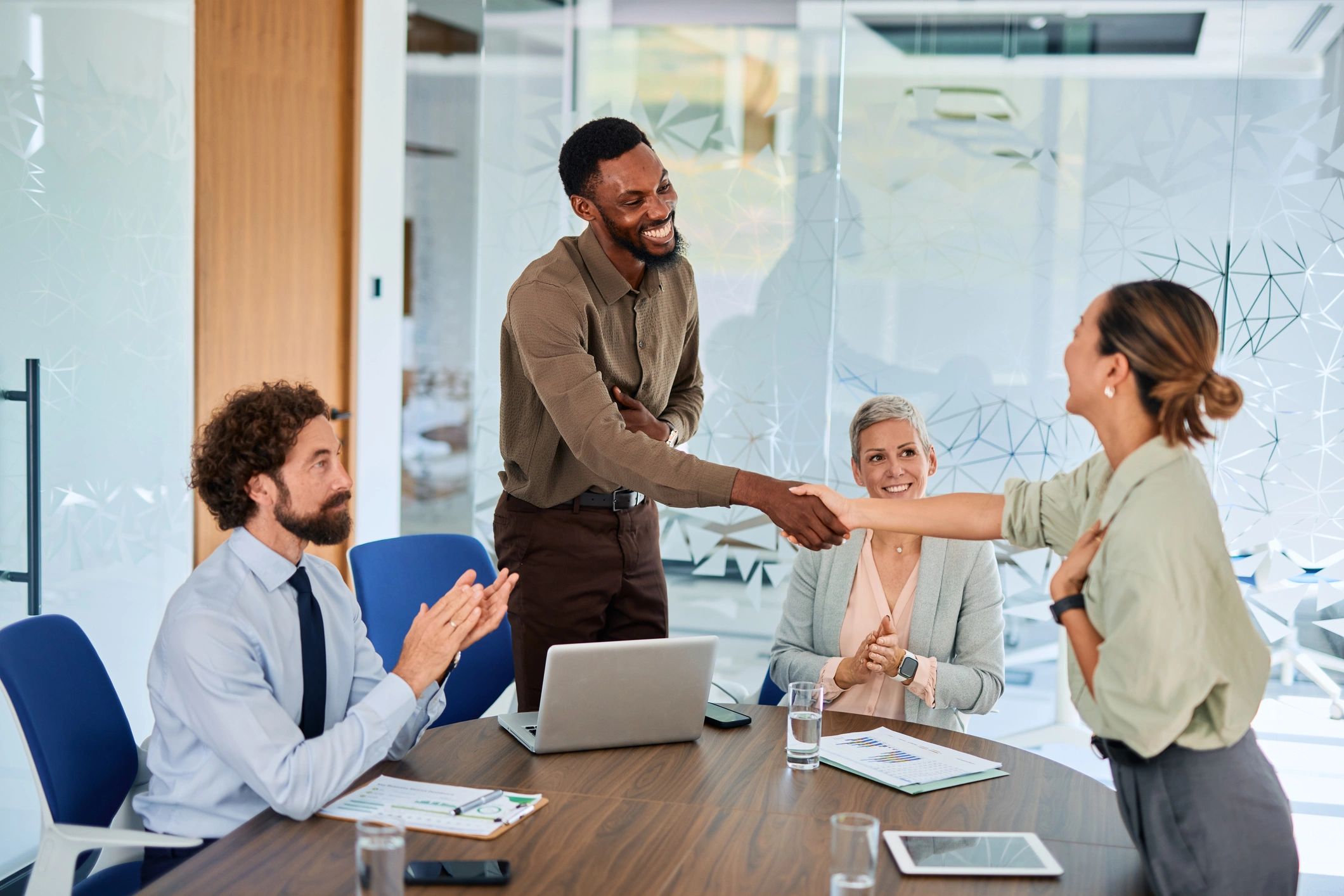 Colleagues shaking hands and applauding in a meeting.