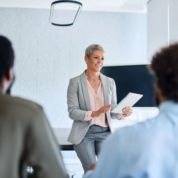 Professional woman leading a presentation using a tablet in a modern office.