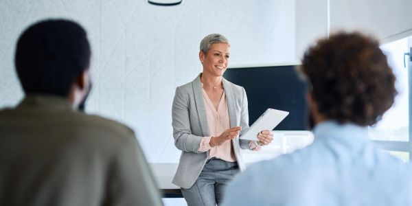 Professional woman presenting to colleagues in a modern office.
