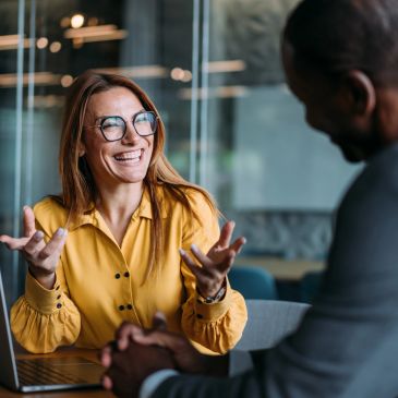 Smiling woman in glasses talking animatedly with a man.