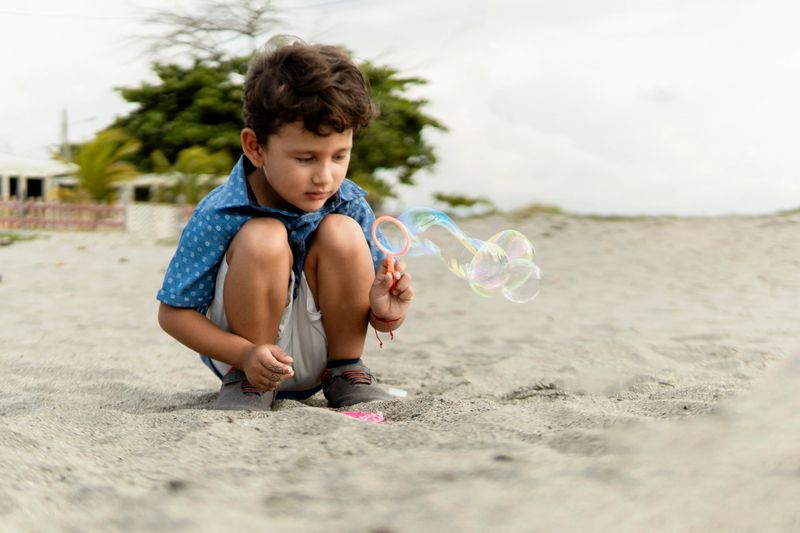 Child playing with soap bubbles on a sandy beach