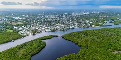 Aerial view of a river separating a green forest and an urban area.