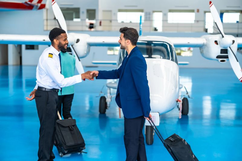 Pilot and a businessman shaking hands in an aircraft hangar, symbolizing a successful business agreement or private flight arrangement