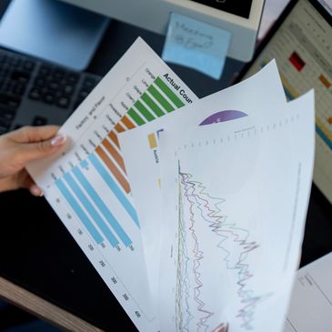 Person analyzing various colorful charts and graphs at a desk.