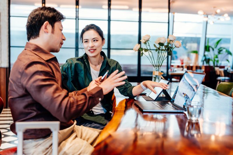 Young Asian businesswoman and businessman having meeting on laptop and working together at cafe. Business persons always busy on the lap top and phone.