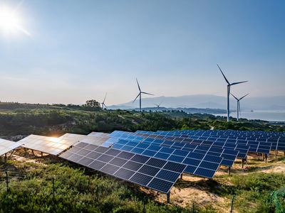 Solar panels and wind turbines generating renewable energy under a clear sky.