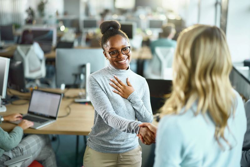 Happy African American female graphic designer came to a successful agreement with her colleague in the office.