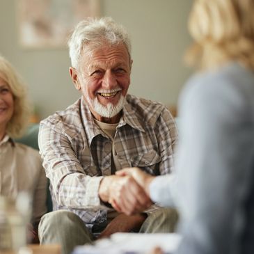 Elderly man smiling and shaking hands.