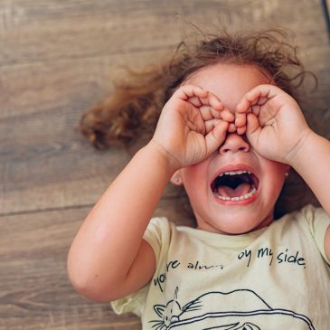 Crying child covering eyes with hands.