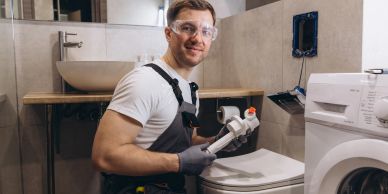Man repairing toilet with plumbing tools.