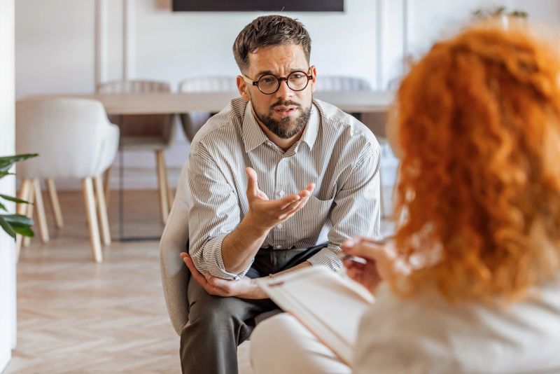 A counselor provides guidance to a client in a contemporary well-lit office space, fostering communication and understanding. Their interaction reflects empathy, focus, and a supportive atmosphere conducive to personal growth.