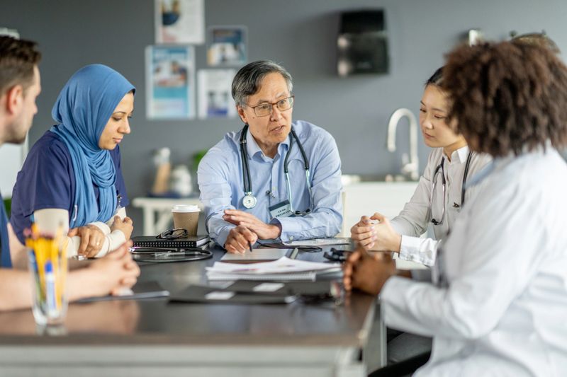 A group of diverse healthcare professionals in discussion, enhancing teamwork and collaboration in a hospital environment. The image highlights diversity and cooperative efforts within the medical field