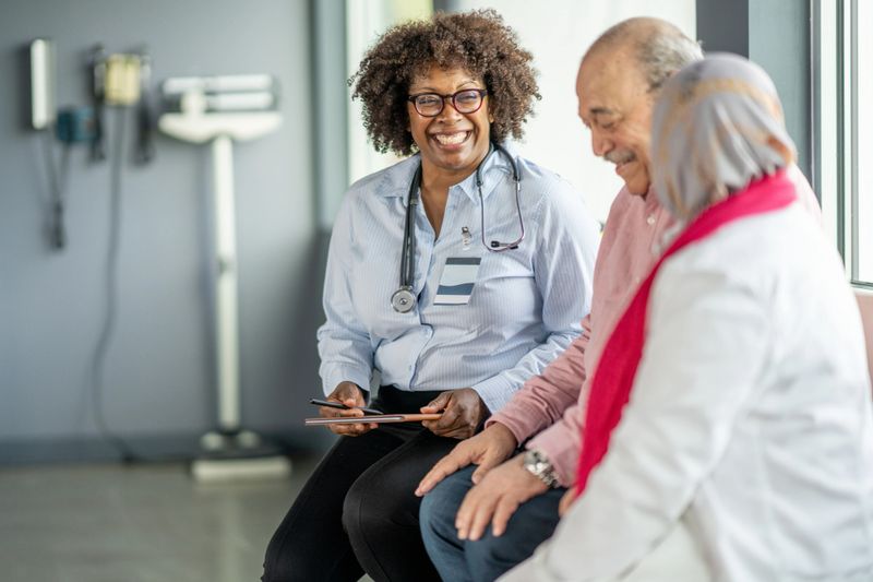 A friendly doctor engaging with two patients in a bright medical office. The atmosphere conveys trust and professionalism, highlighting healthcare relationships.
