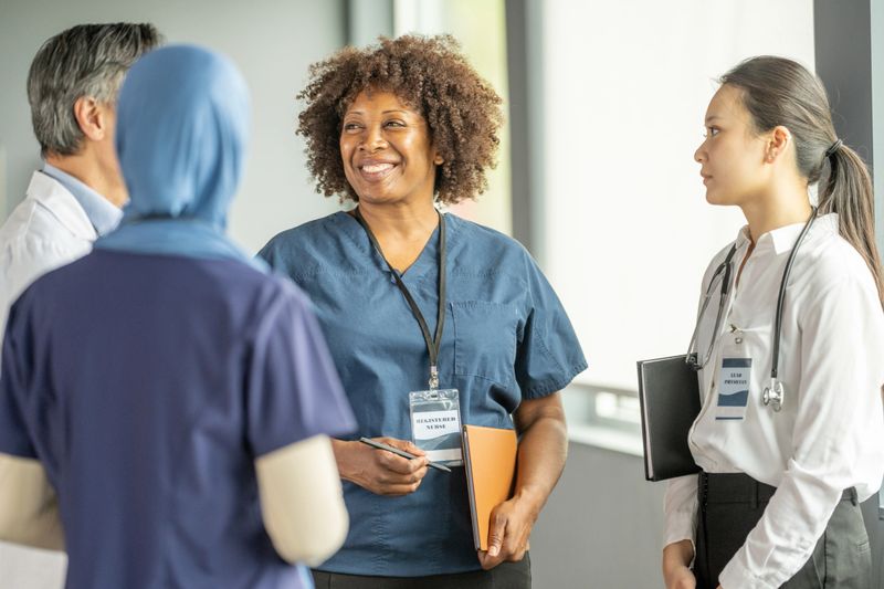 Diverse group of medical professionals conversing in a modern setting, fostering collaboration and teamwork. The image features friendly and engaged healthcare workers expressing professionalism and shared focus on objectives.