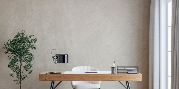 Minimalist office desk with plant and lamp.