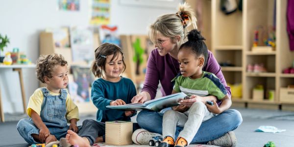 Teacher reading a book with children in a classroom.
