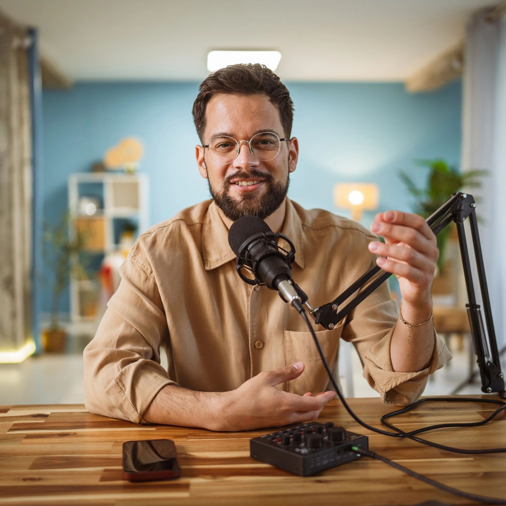 Man recording a podcast with a microphone in a cozy room.