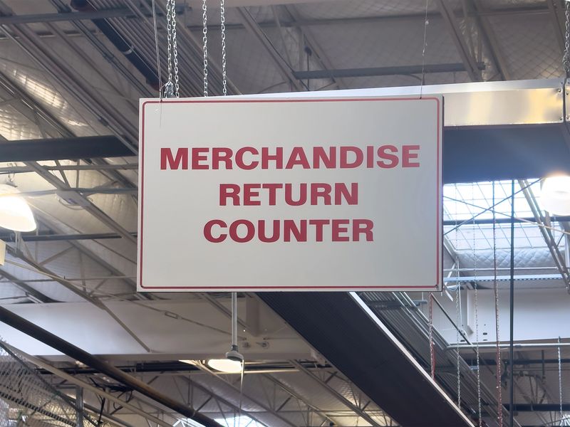 A clear "MERCHANDISE RETURN COUNTER" sign hangs in a large retail space, guiding customers through the post-purchase experience with clarity.