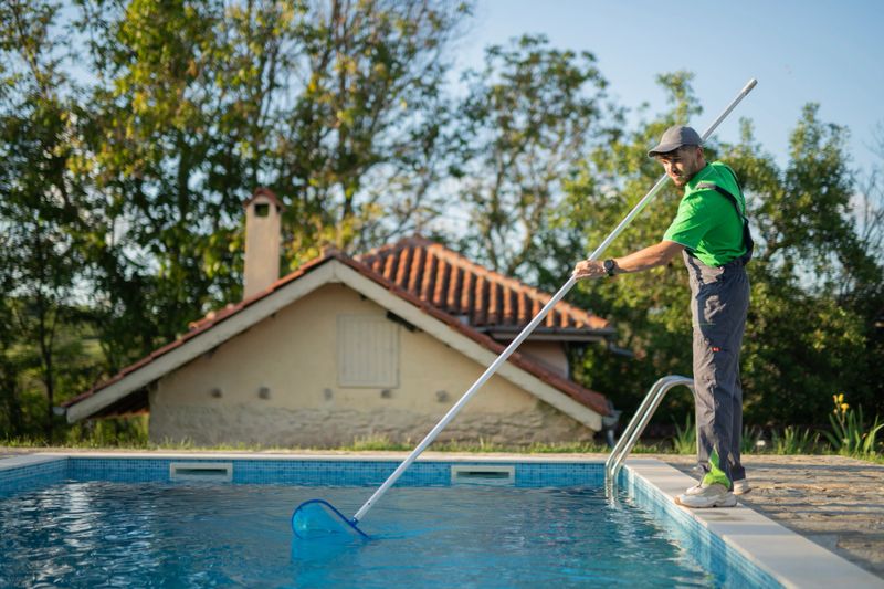 Male worker swimming pools maintainer is hired to clean out a pool in a private house.