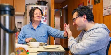 Two people sharing a joyful moment at a kitchen table.