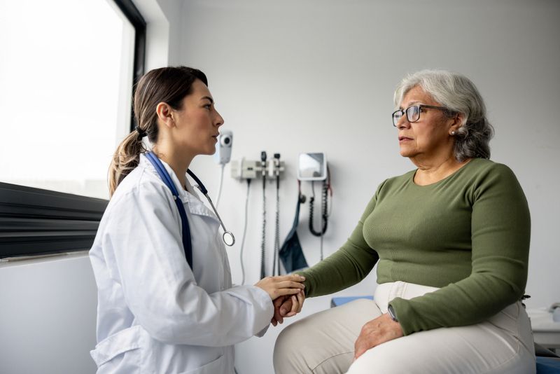 Latin American doctor consoling a senior woman and holding her hand in the consultation room -healthcare and medicine concepts