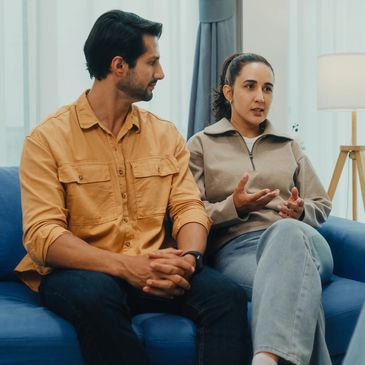 A couple having a serious conversation on a blue couch.