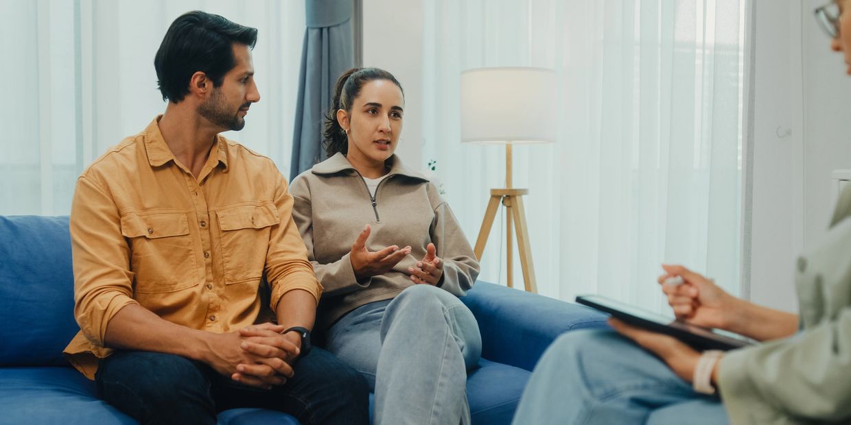 A couple discussing their feelings with a therapist in a cozy room.