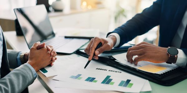 Two professionals discuss annual growth charts at a desk.